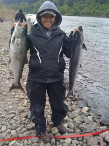 Aja DeCoteau holds Salmon along the banks of a northwest river.
