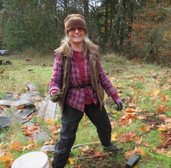 donor photo woman in beanie and plaid shirt standing on grass with many leaves