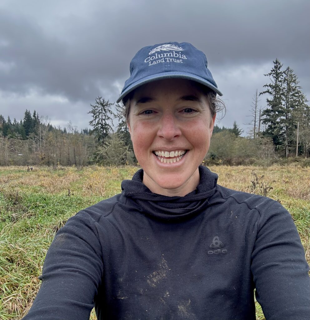 person with mud splatters wearing land trust hat