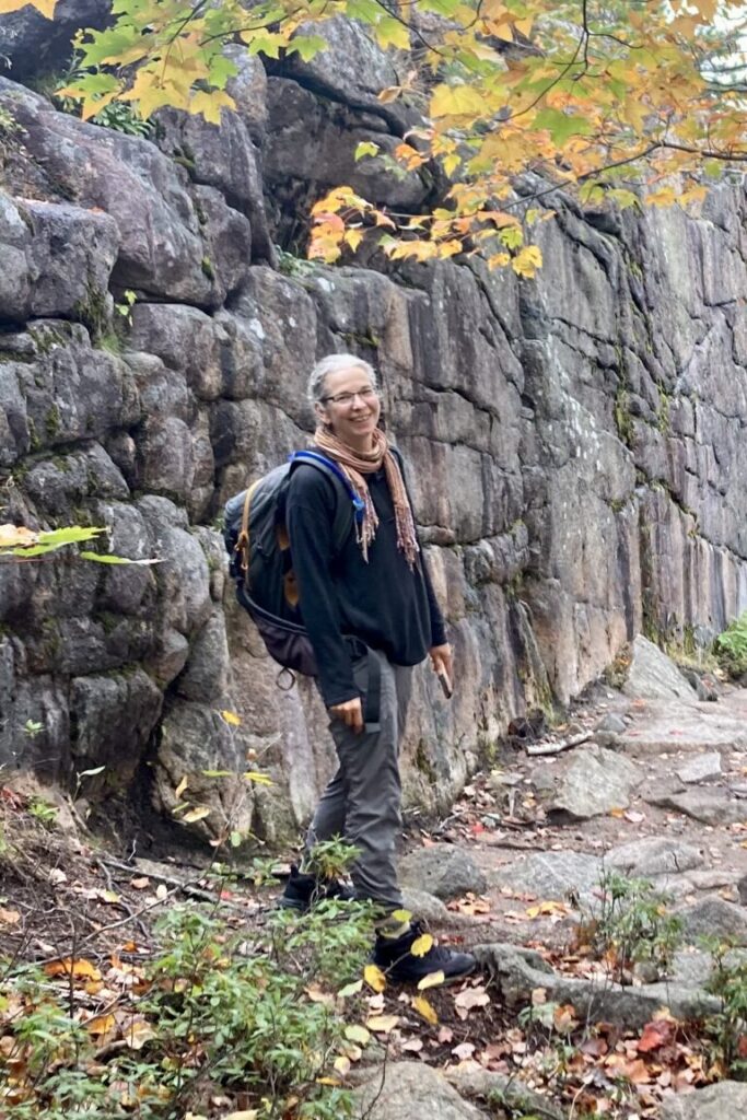 karen wearing a backpack in front of a rock face