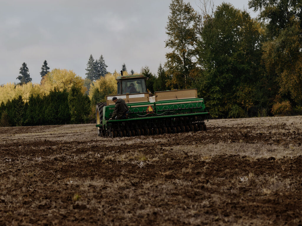 a tractor tills flat land as part of a native plant restoration project
