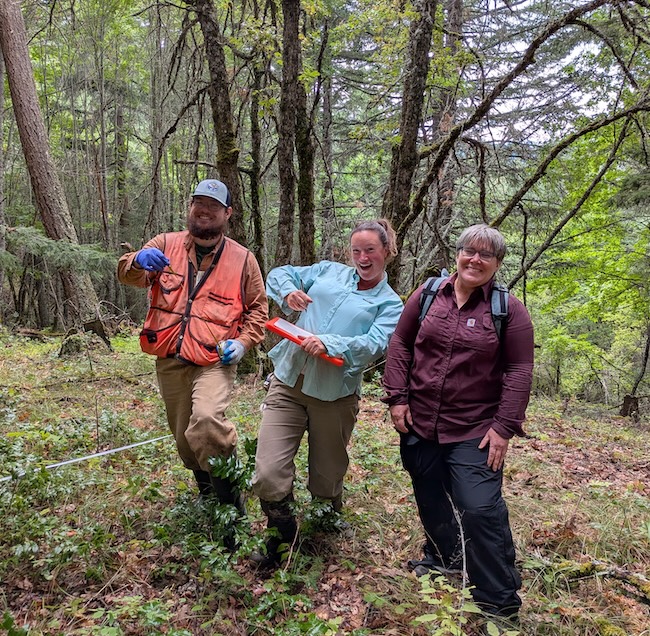 ethan and two other members of the oak partners stand, smiling, in an oak woodland, one holds a clipboard