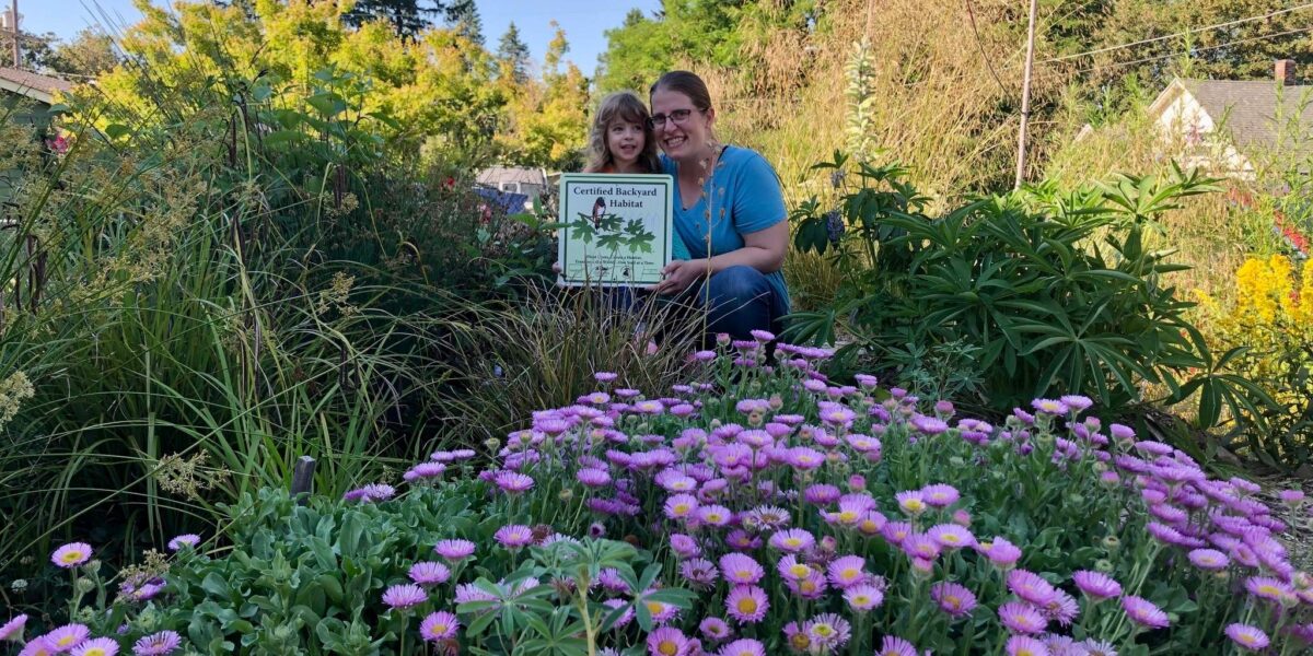 Backyard Habitat participant with a sign